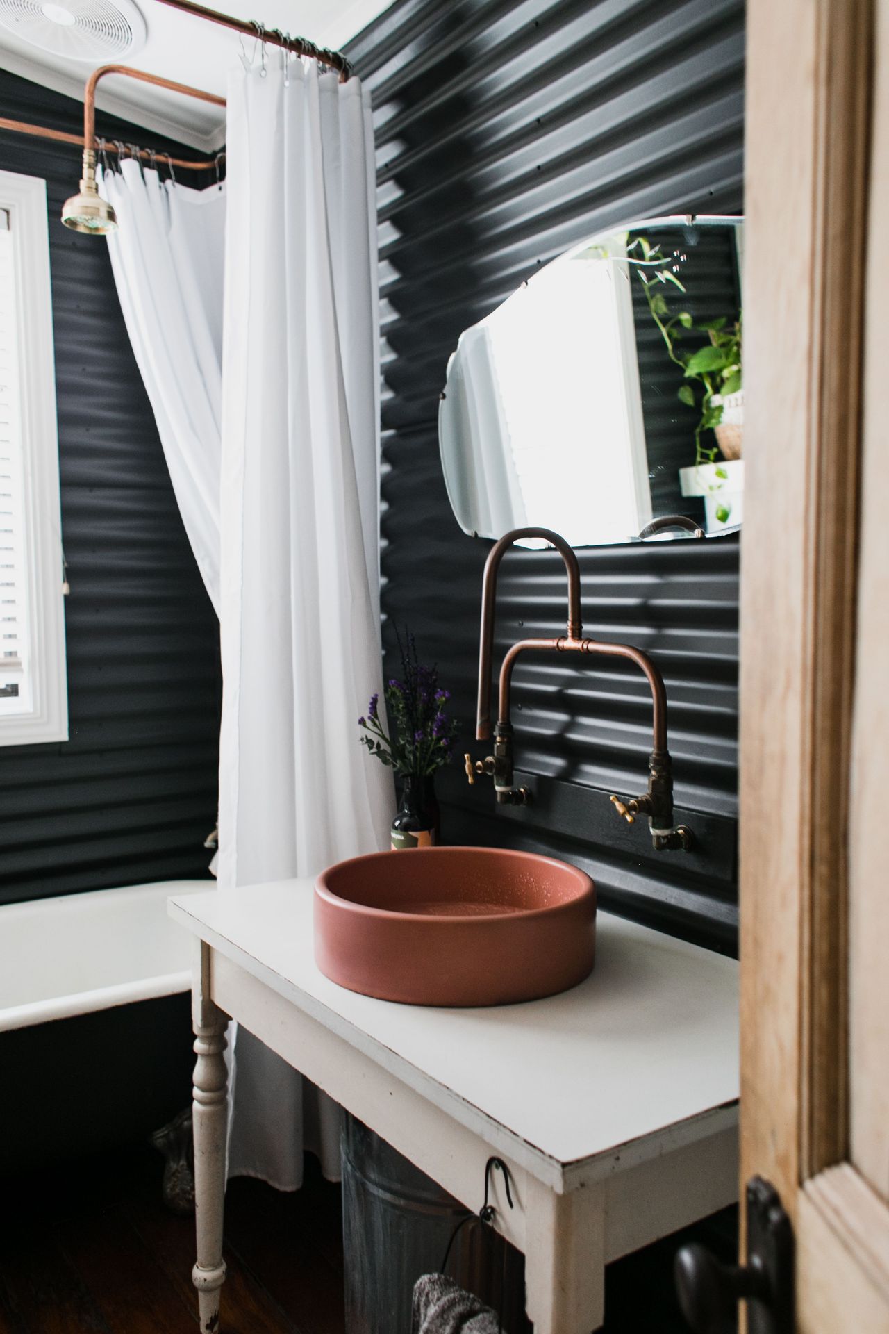 Bathroom with a ceramic basin, mirror and copper fixture plumbing